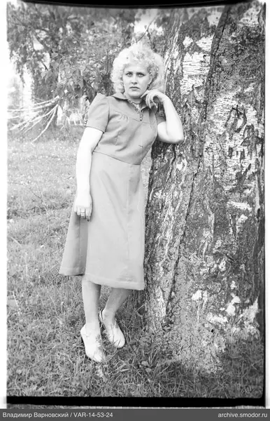 Frau an einer Birke in einem kurzen Kleid