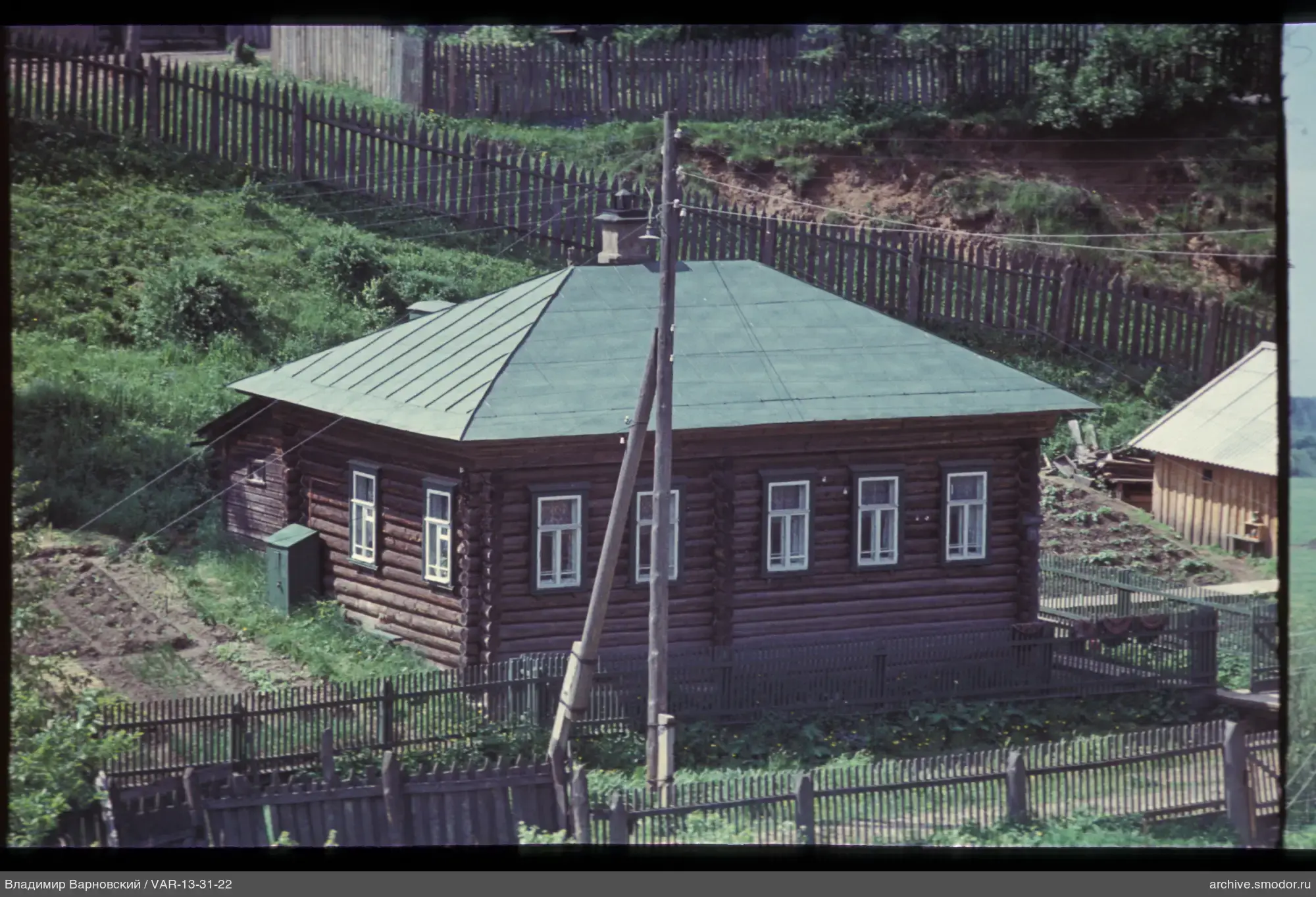 Holzhaus mit grünem Dach und Zaun