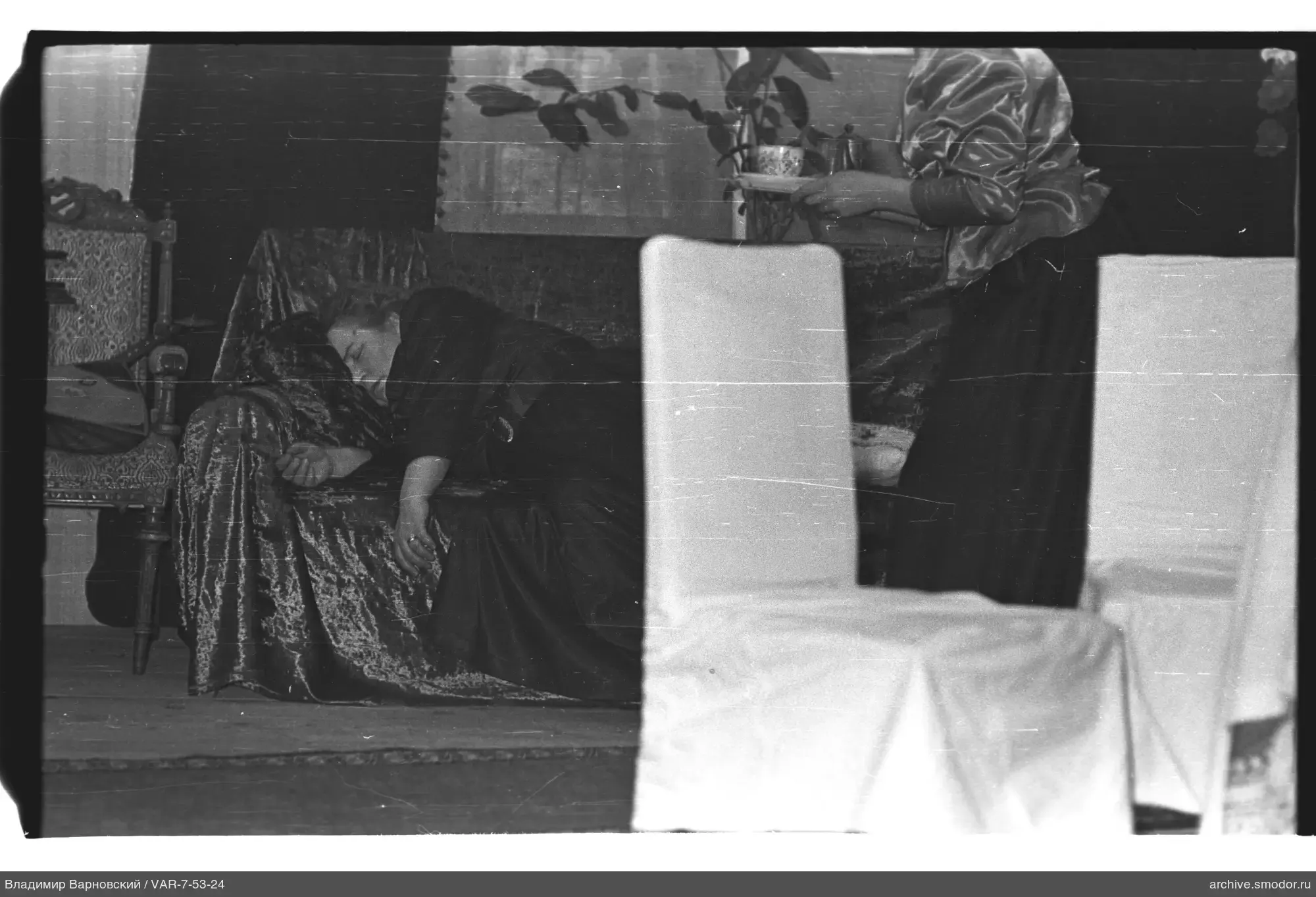 Frau auf Sofa und Frau mit Tablett