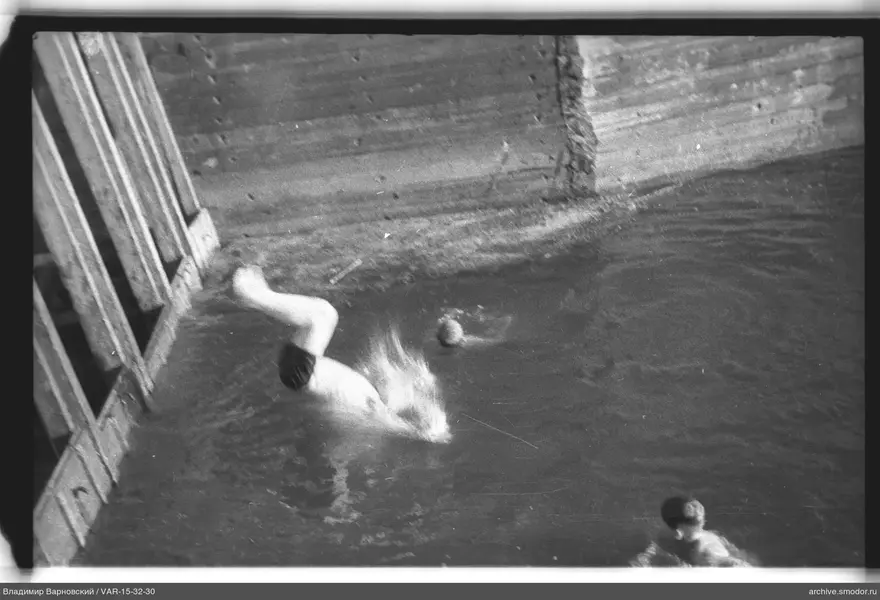 Jungen im Wasser bei einem Holzsteg