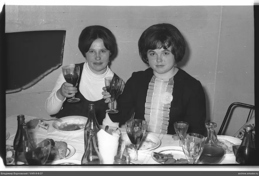 Две женщины за столом с посудой и напитками