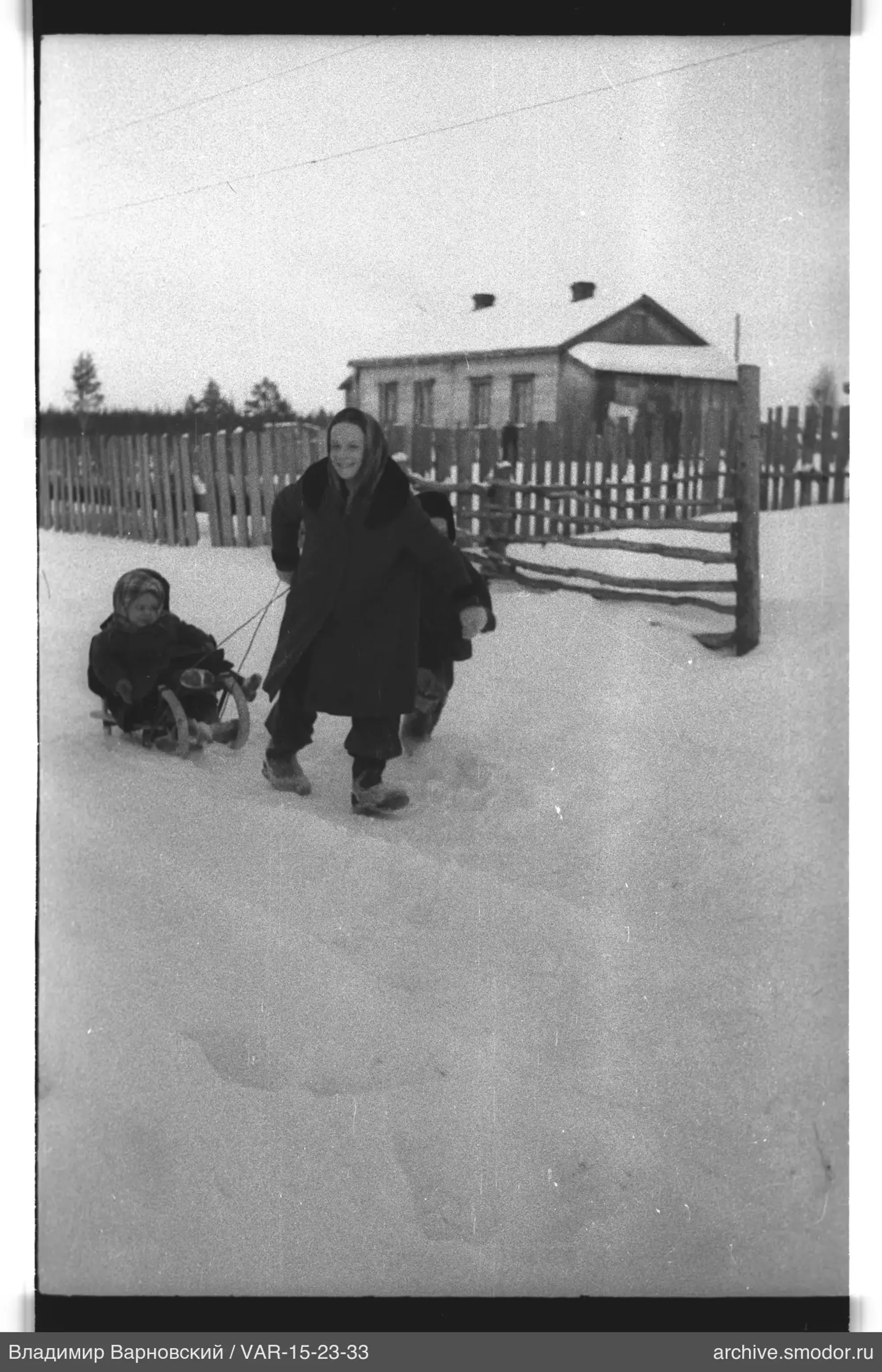 Женщина с санками и детьми на снегу