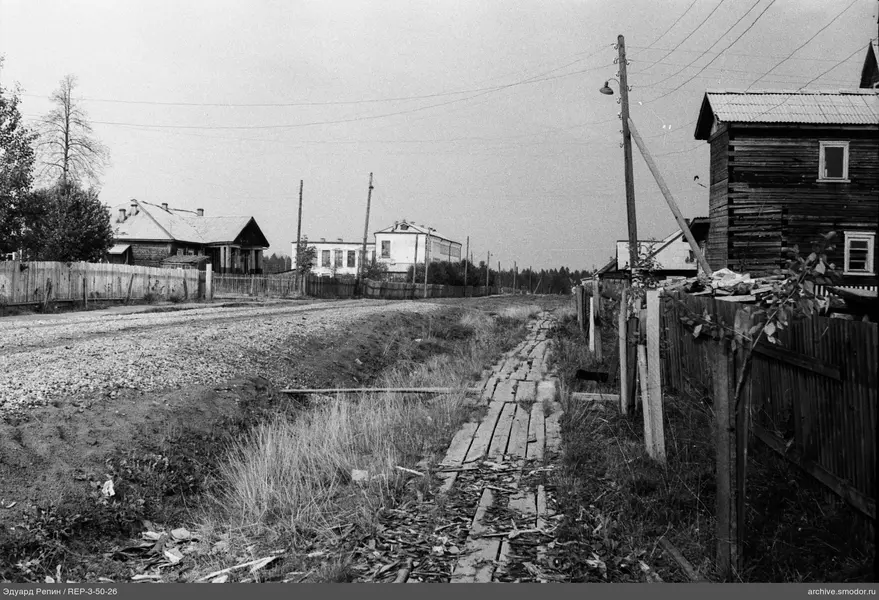 Schotterstraße mit Häusern und Stromleitungen