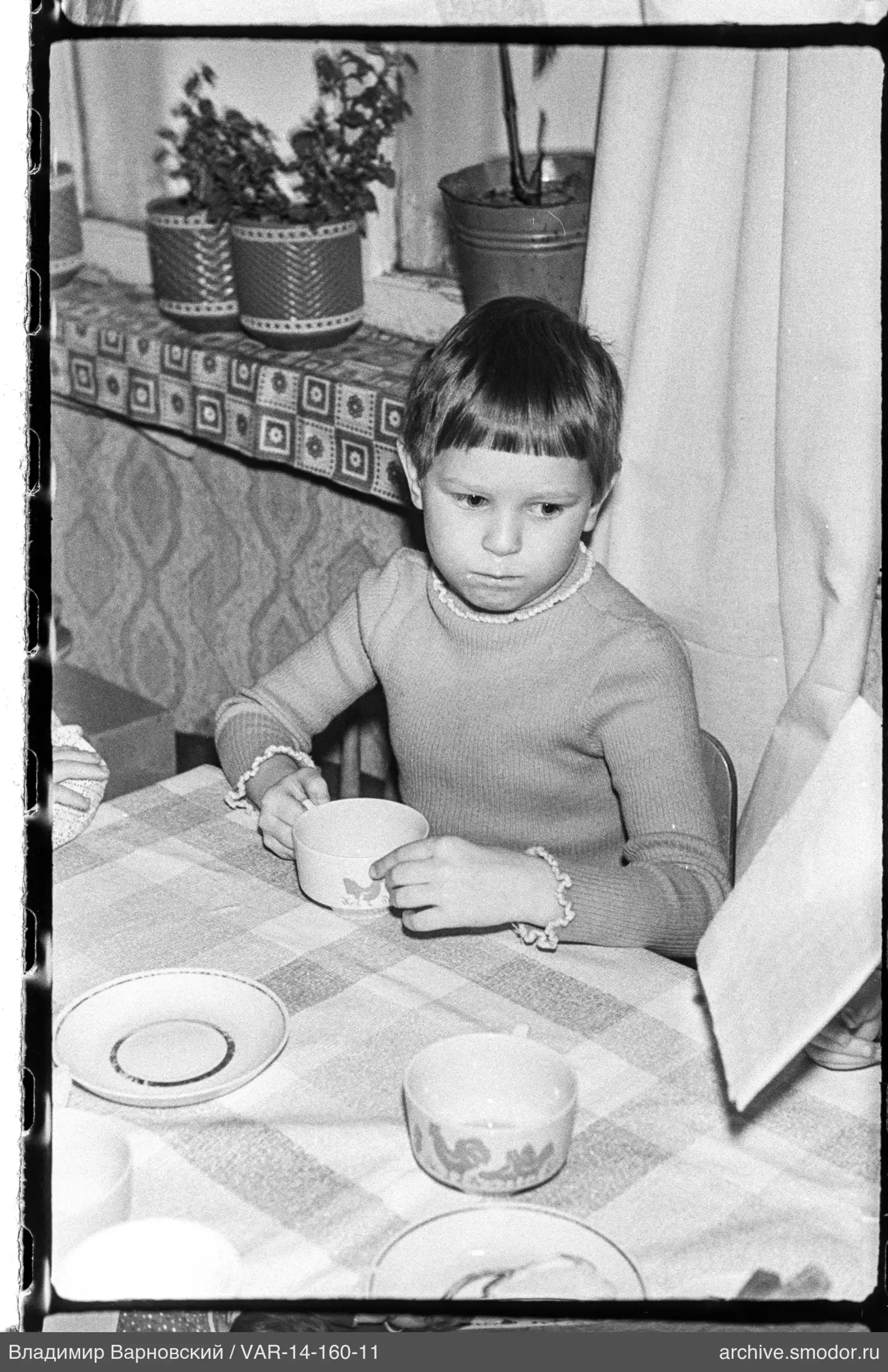 Kind mit Tasse am Tisch