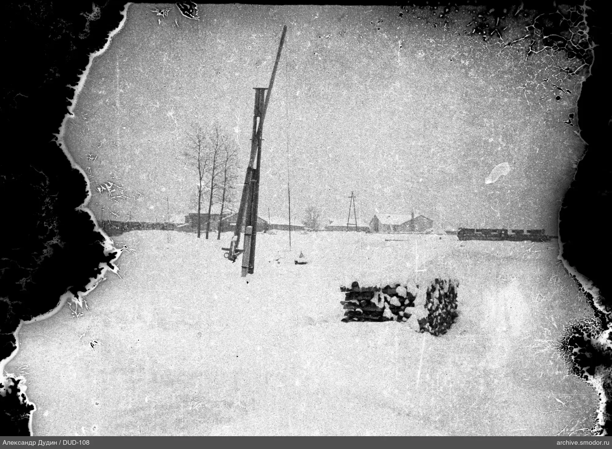 Schneebedecktes Feld mit Holzstapeln und Holzkonstruktion