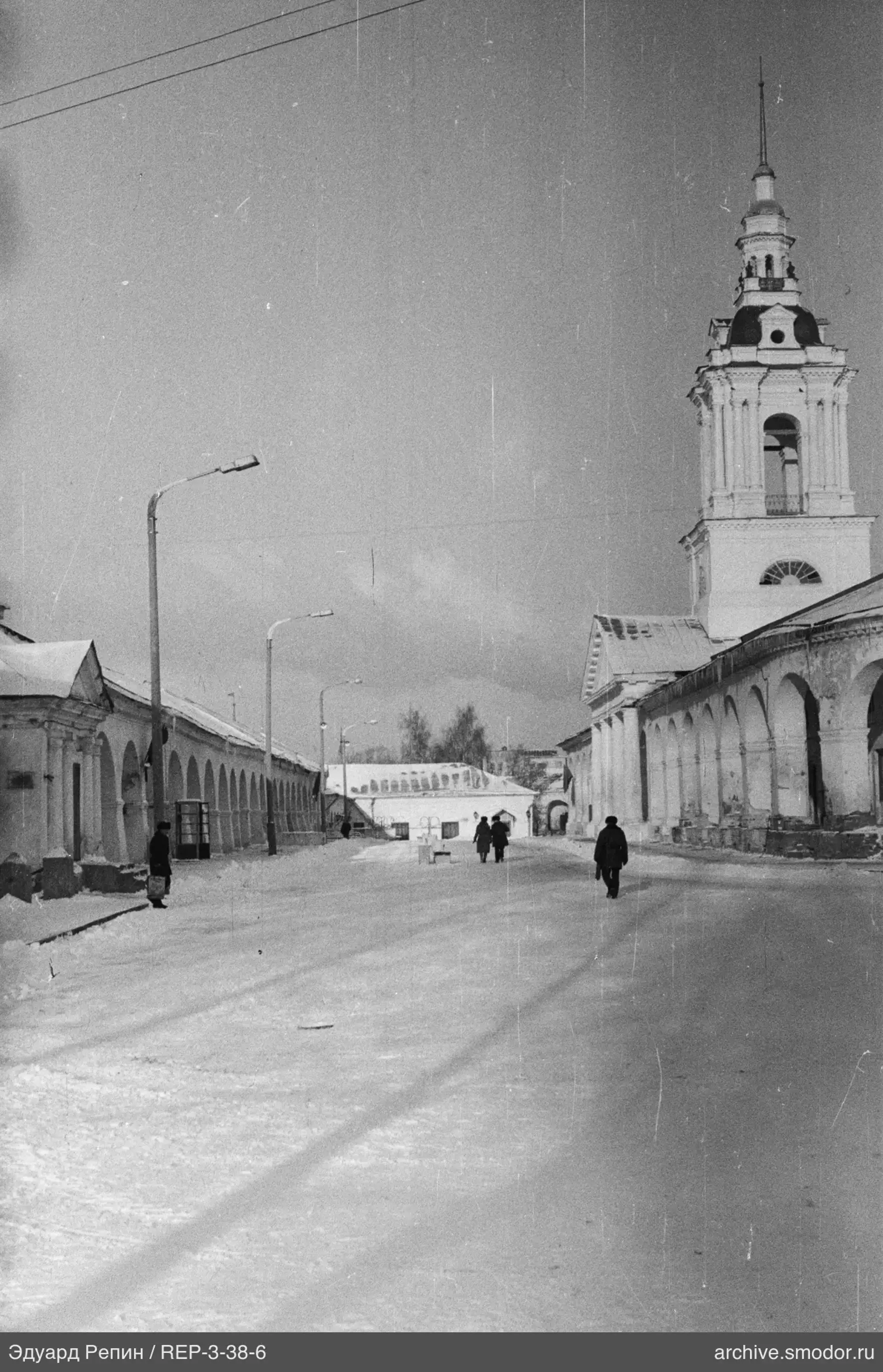 Заснеженная улица между зданиями с арками