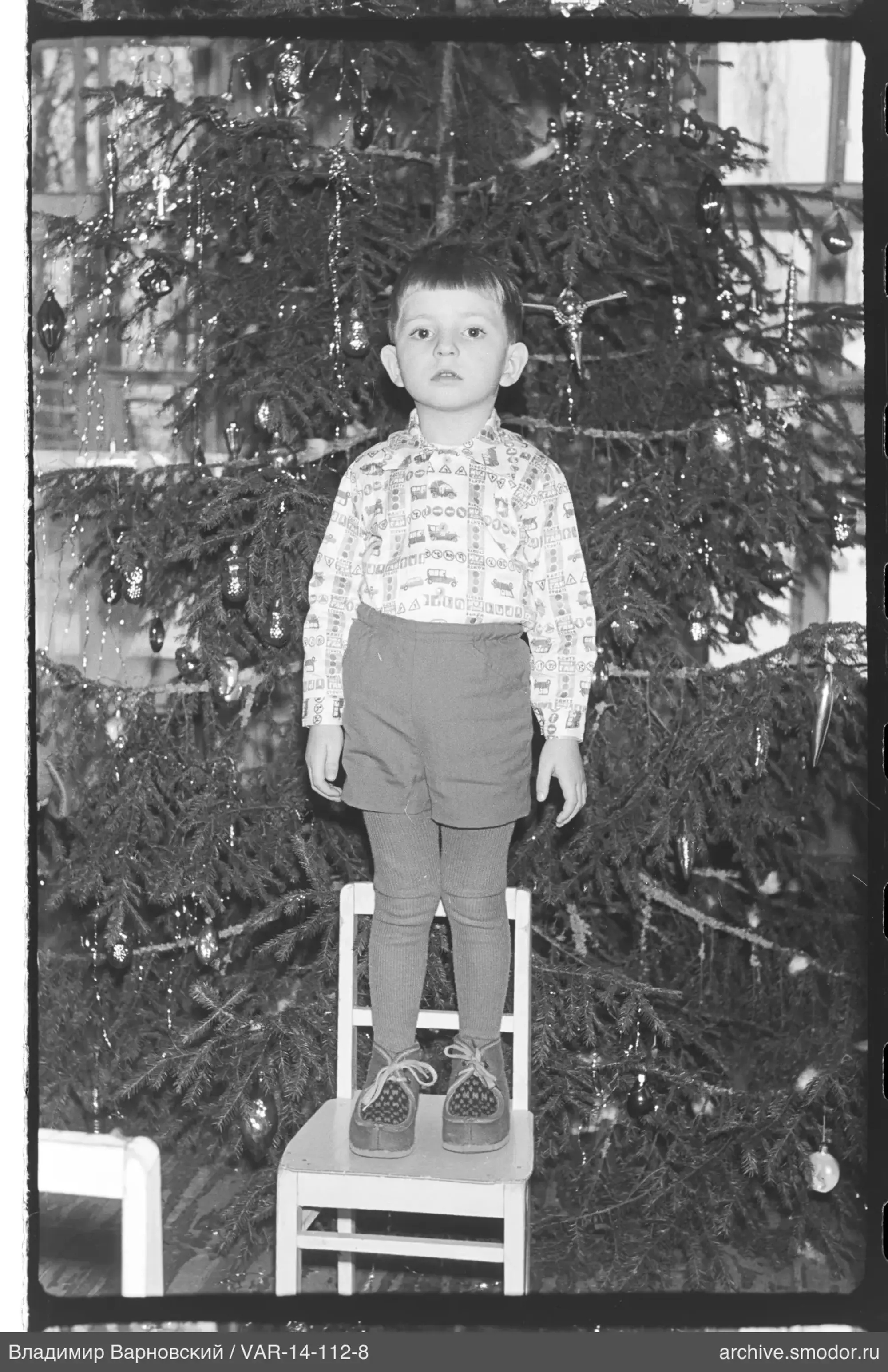 Junge vor geschmücktem Weihnachtsbaum