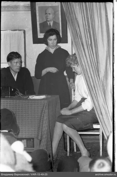 Three people in a room with a portrait