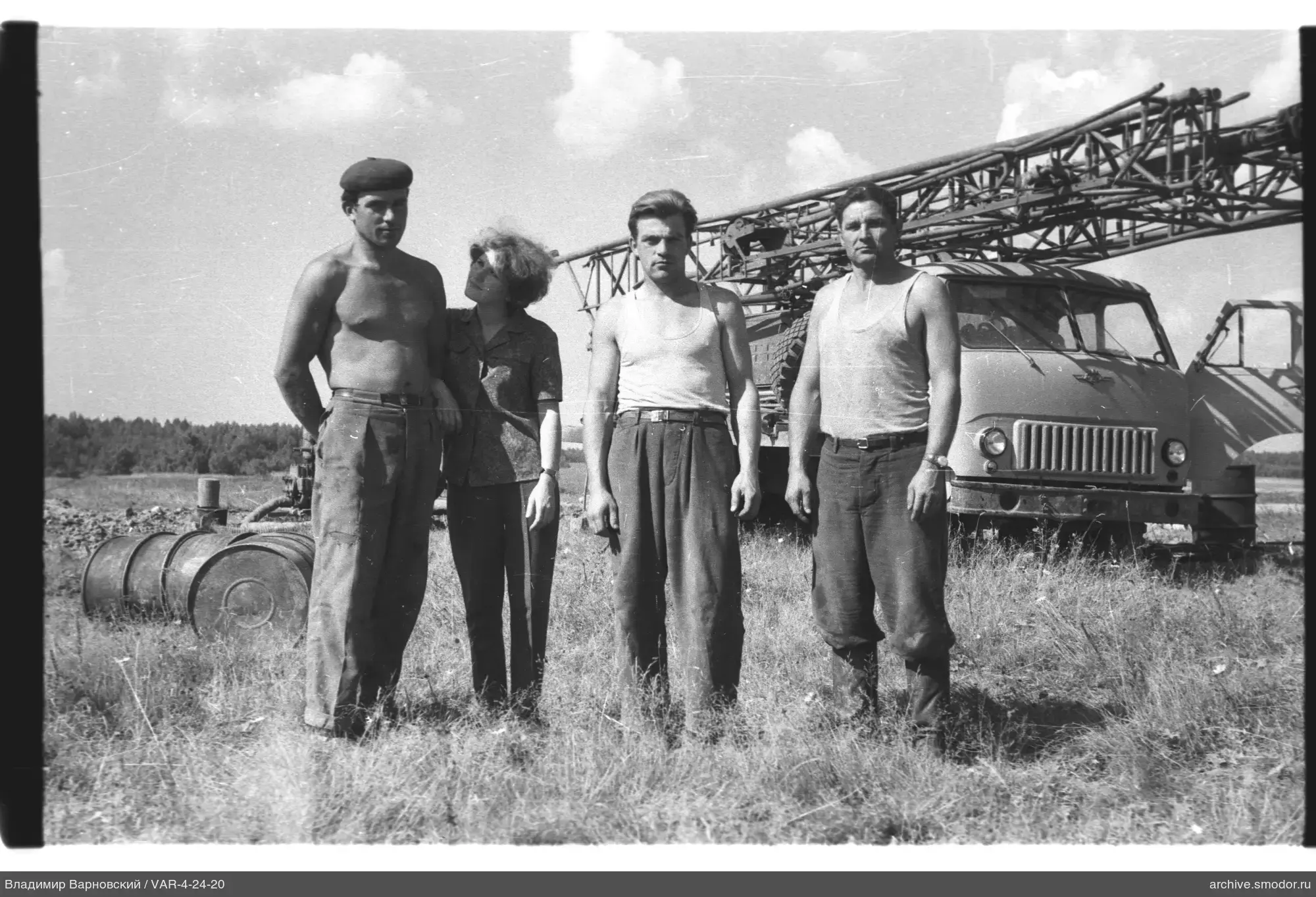 Gruppe von Menschen auf Feld mit LKW und Wald