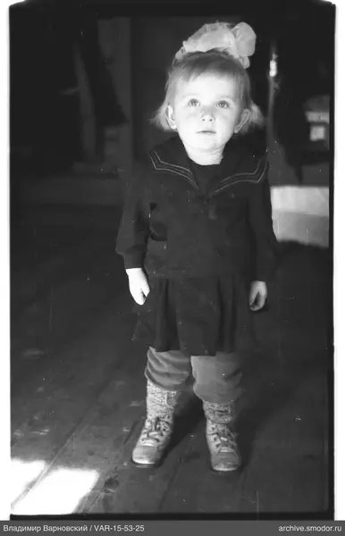 Mädchen in dunklem Kleid mit Schleife und hellen Socken