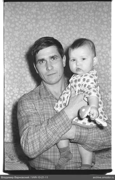 Man with a child against floral wallpaper