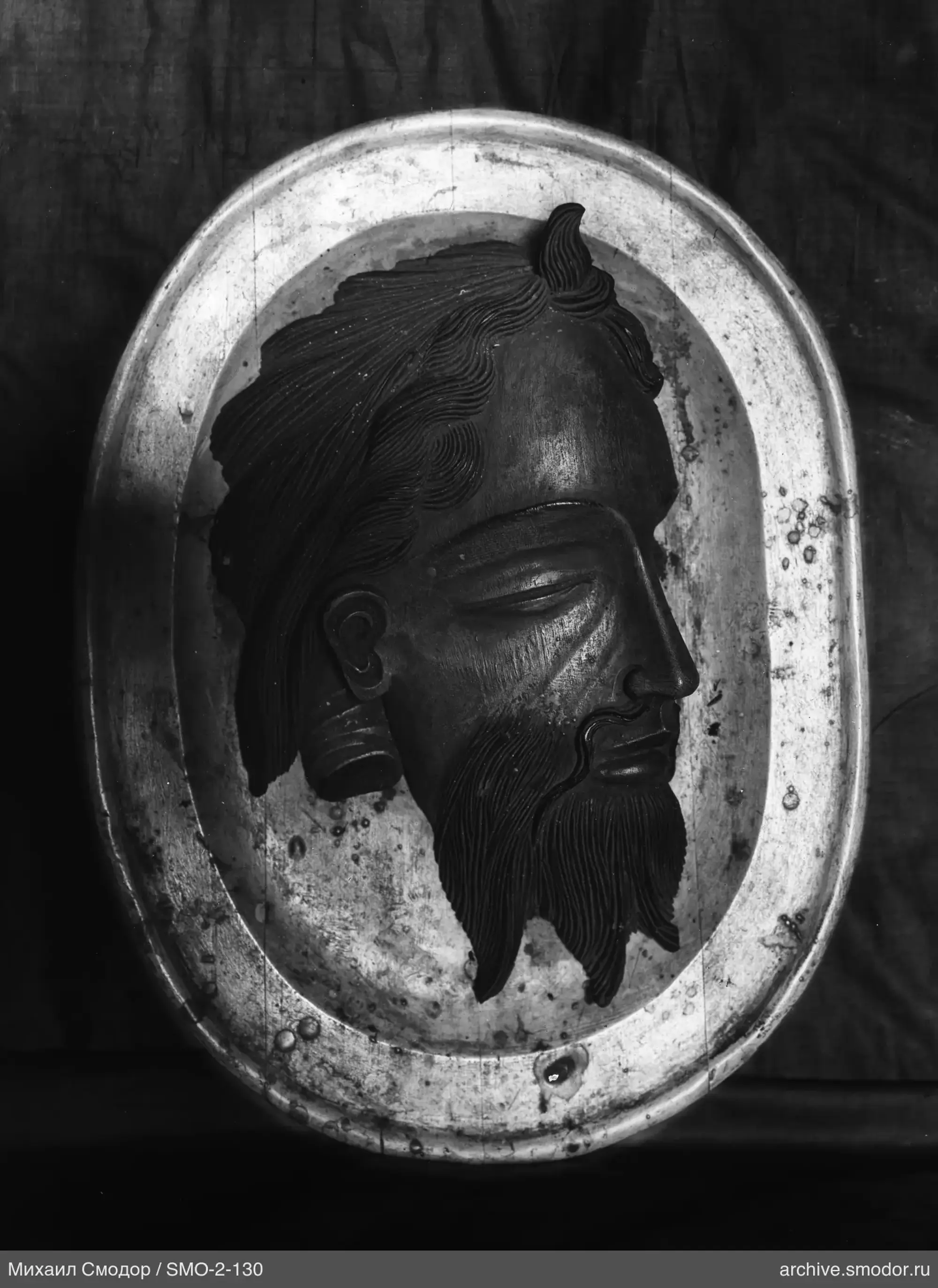 Oval metal plate with male profile relief