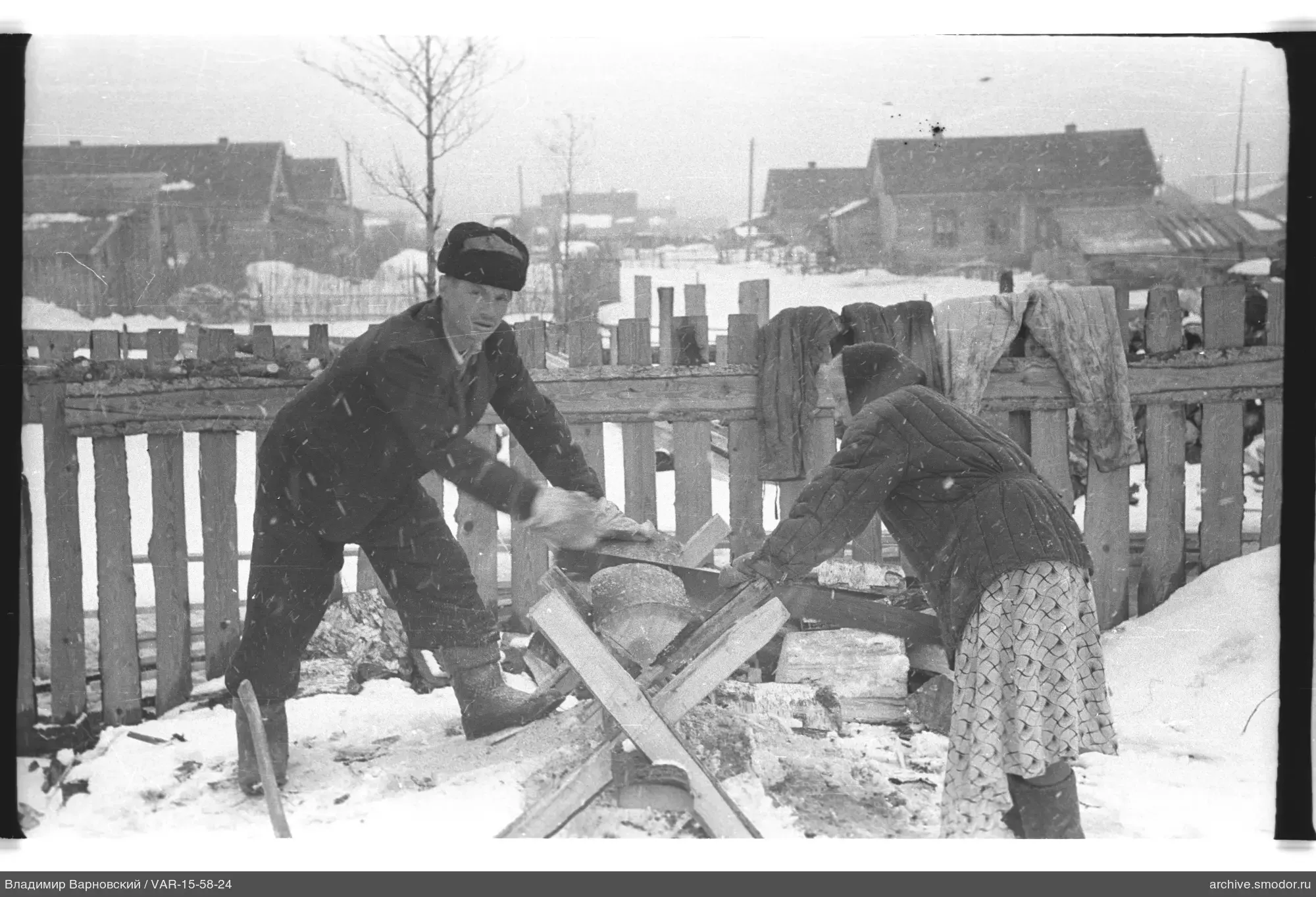 Mann und Frau hacken Holz am Zaun