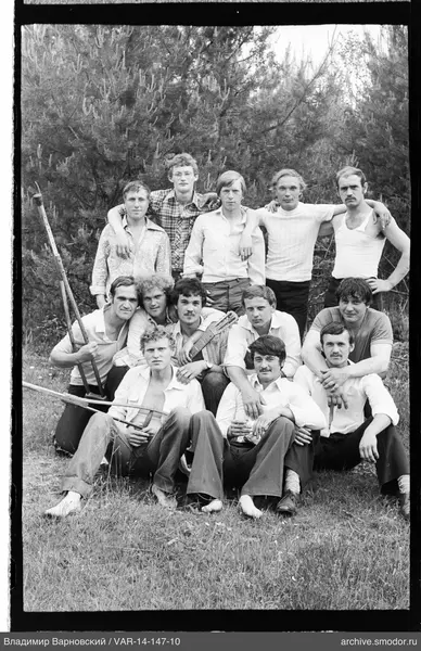 Group of men on grass with conifers in background
