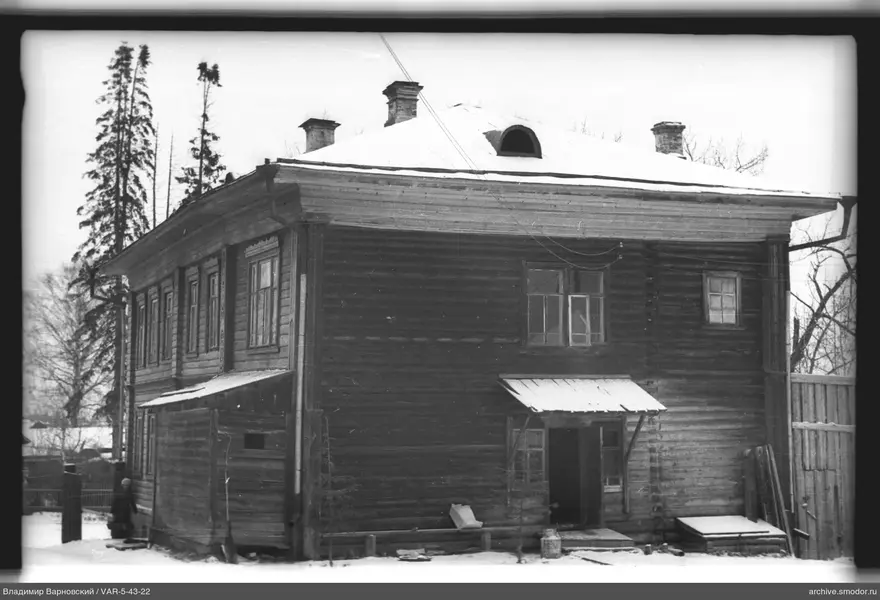 Zweistöckiges Holzhaus mit Schnee und Person