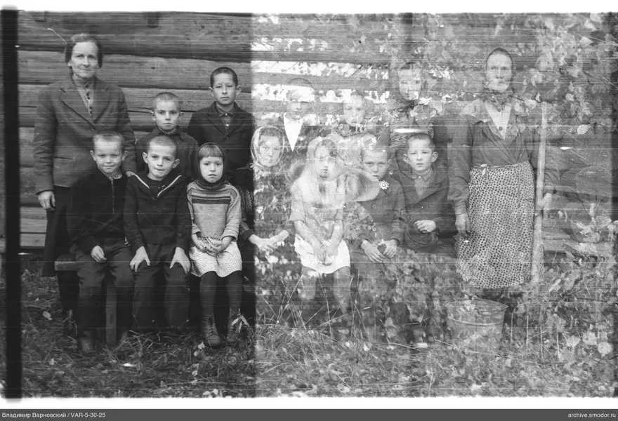 Gruppe von Kindern und Frauen vor Holzwand