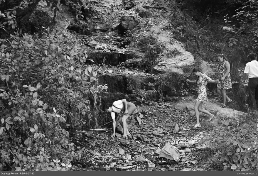 Menschen am felsigen Hang mit Wasserfall
