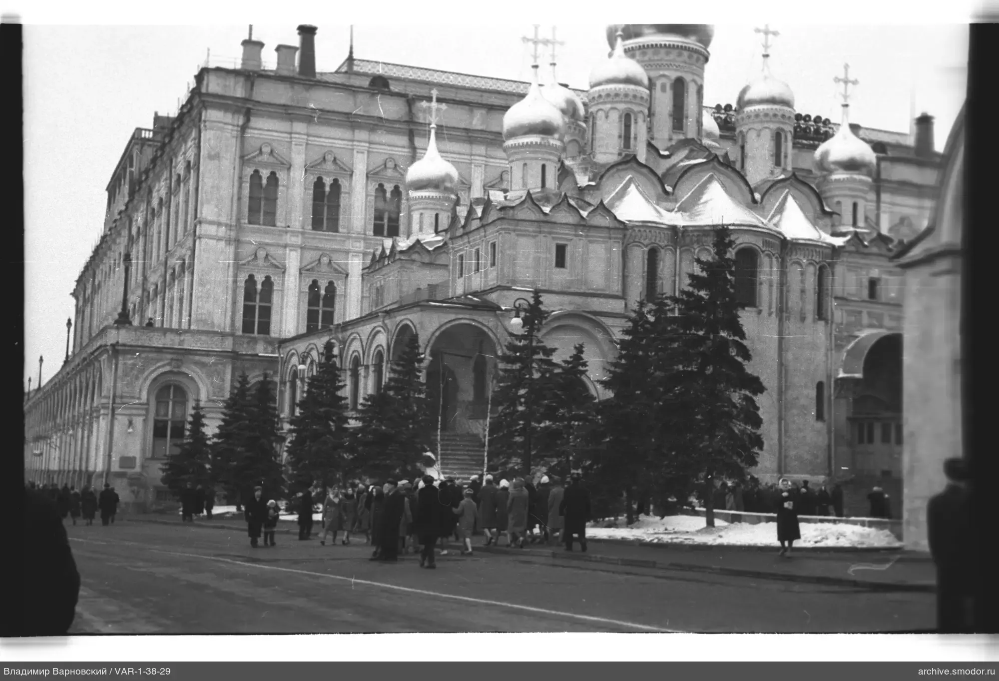 Группа людей у здания с арочными окнами и церковью