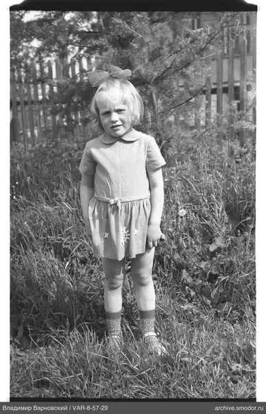 Mädchen im Kleid mit Schleife auf Gras