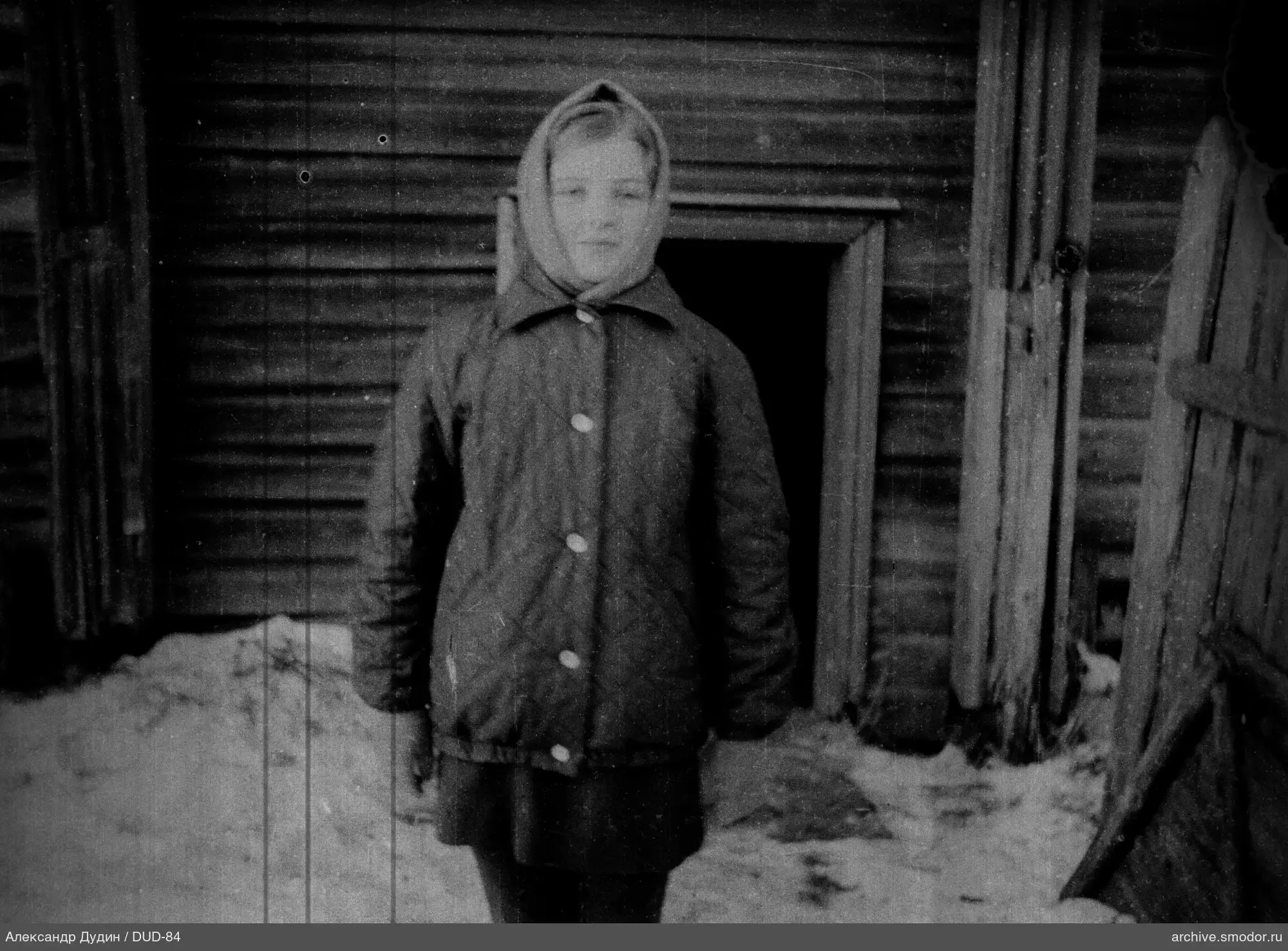 Porträt einer Frau vor einem Holzhaus im Schnee