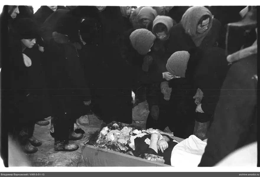 Группа женщин у деревянного гроба на снегу