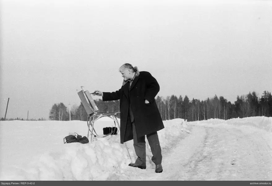 Mann malt auf einer Staffelei im Schnee