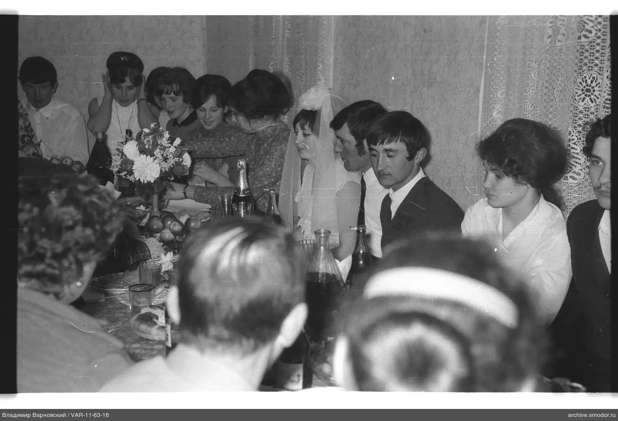 Group portrait with woman in wedding dress at table