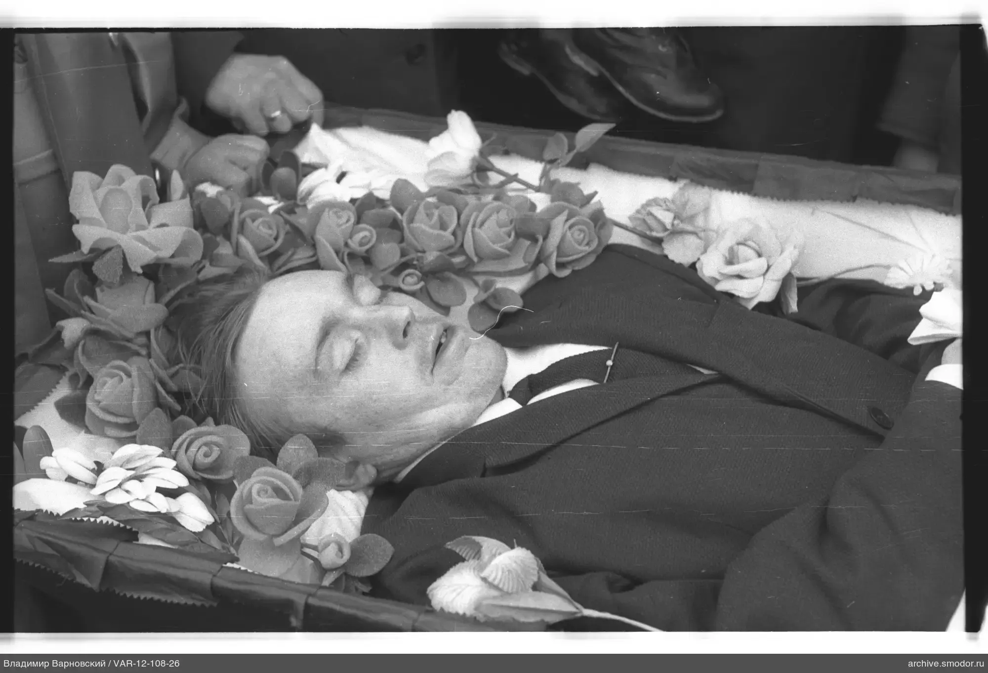 Mann im Sarg mit künstlichen Blumen