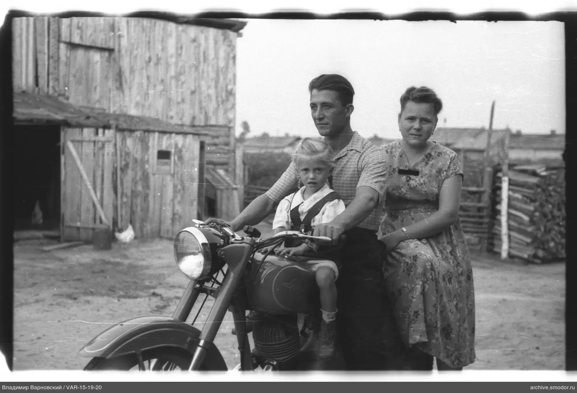 Gruppe mit Motorrad vor Holzgebäude