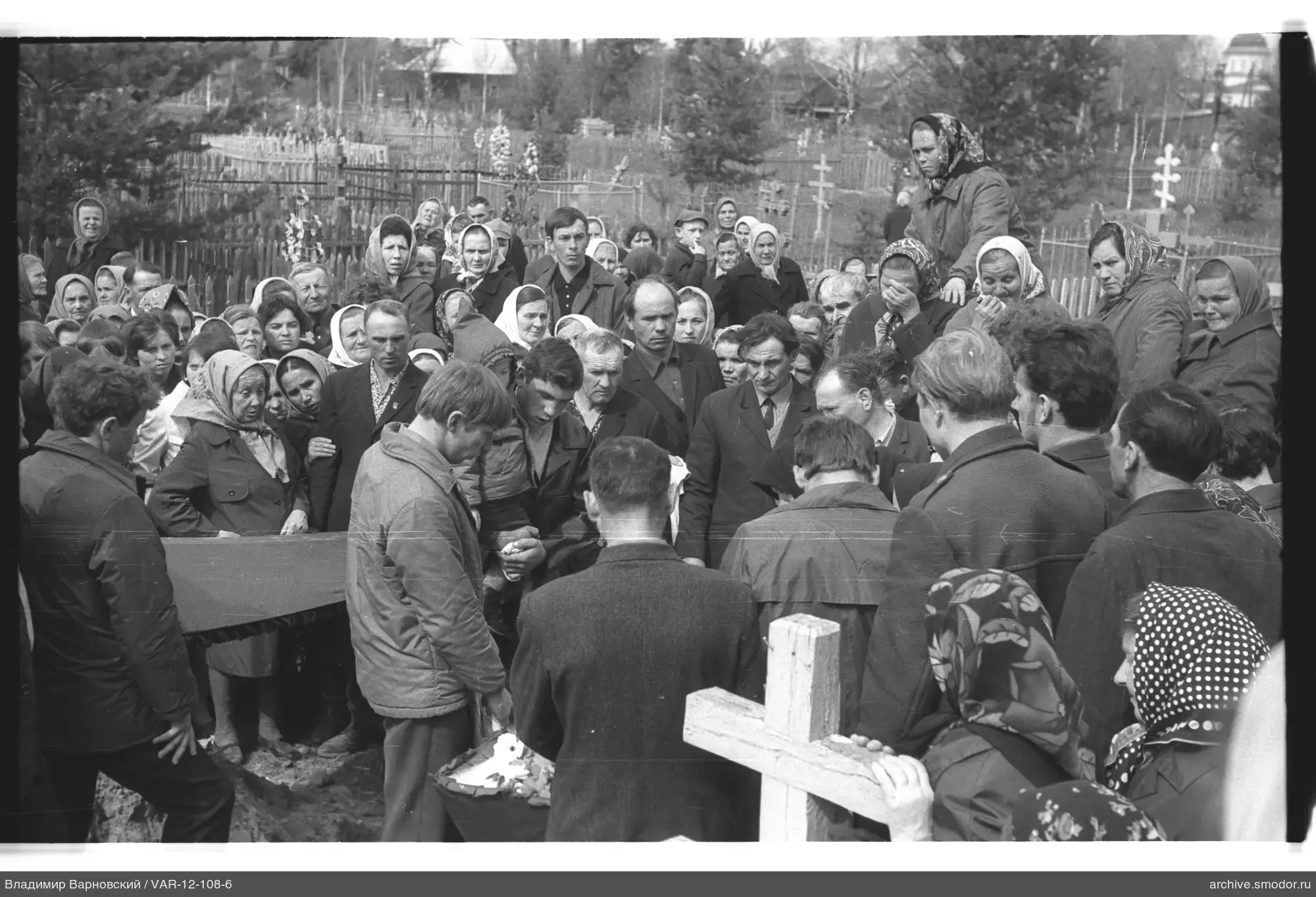 Gruppe von Menschen um einen offenen Sarg auf dem Friedhof