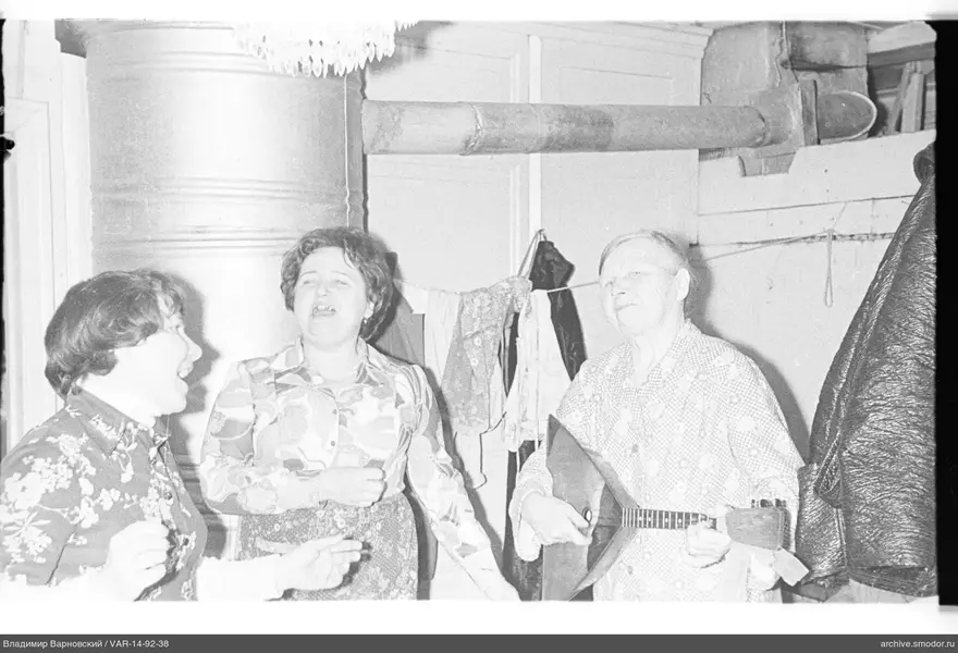 Three women in a room, one playing balalaika