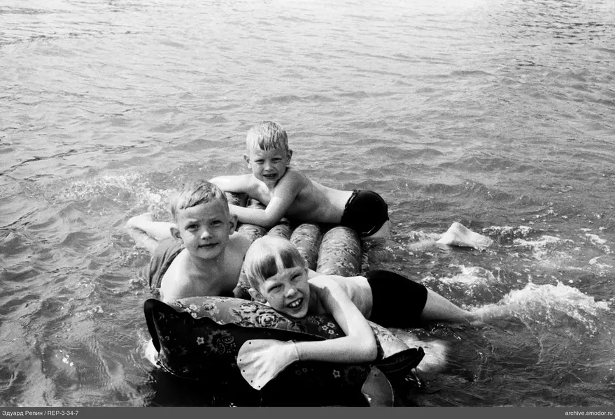 Drei Jungen auf einer aufblasbaren Matte im Wasser
