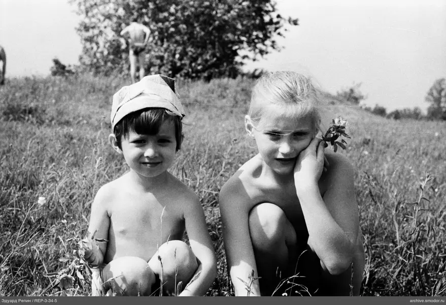 Kinder mit Blumen und Mann im Hintergrund