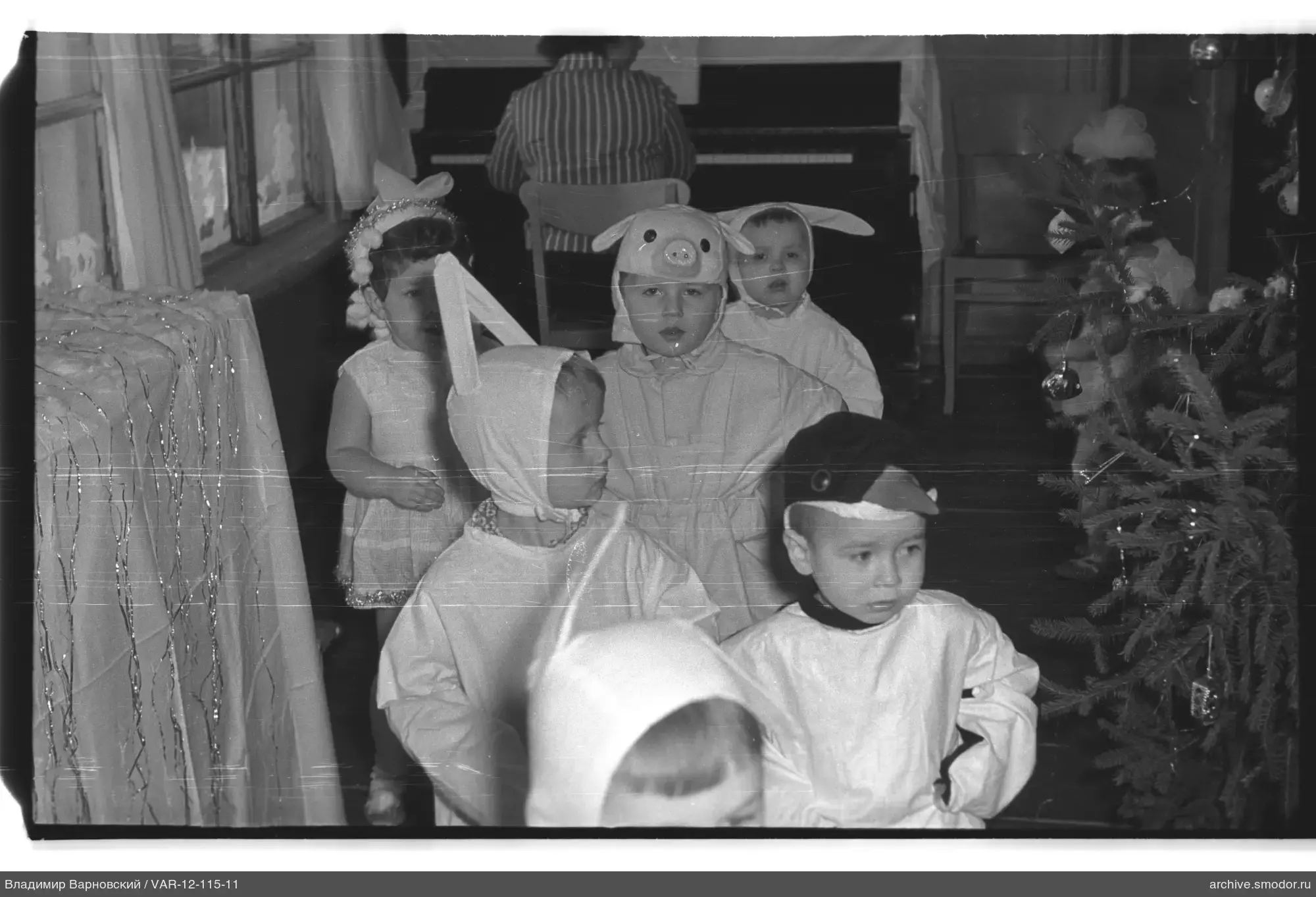 Children in costumes with Christmas tree and piano