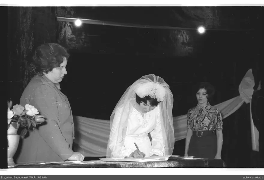 Woman in white dress signing a document
