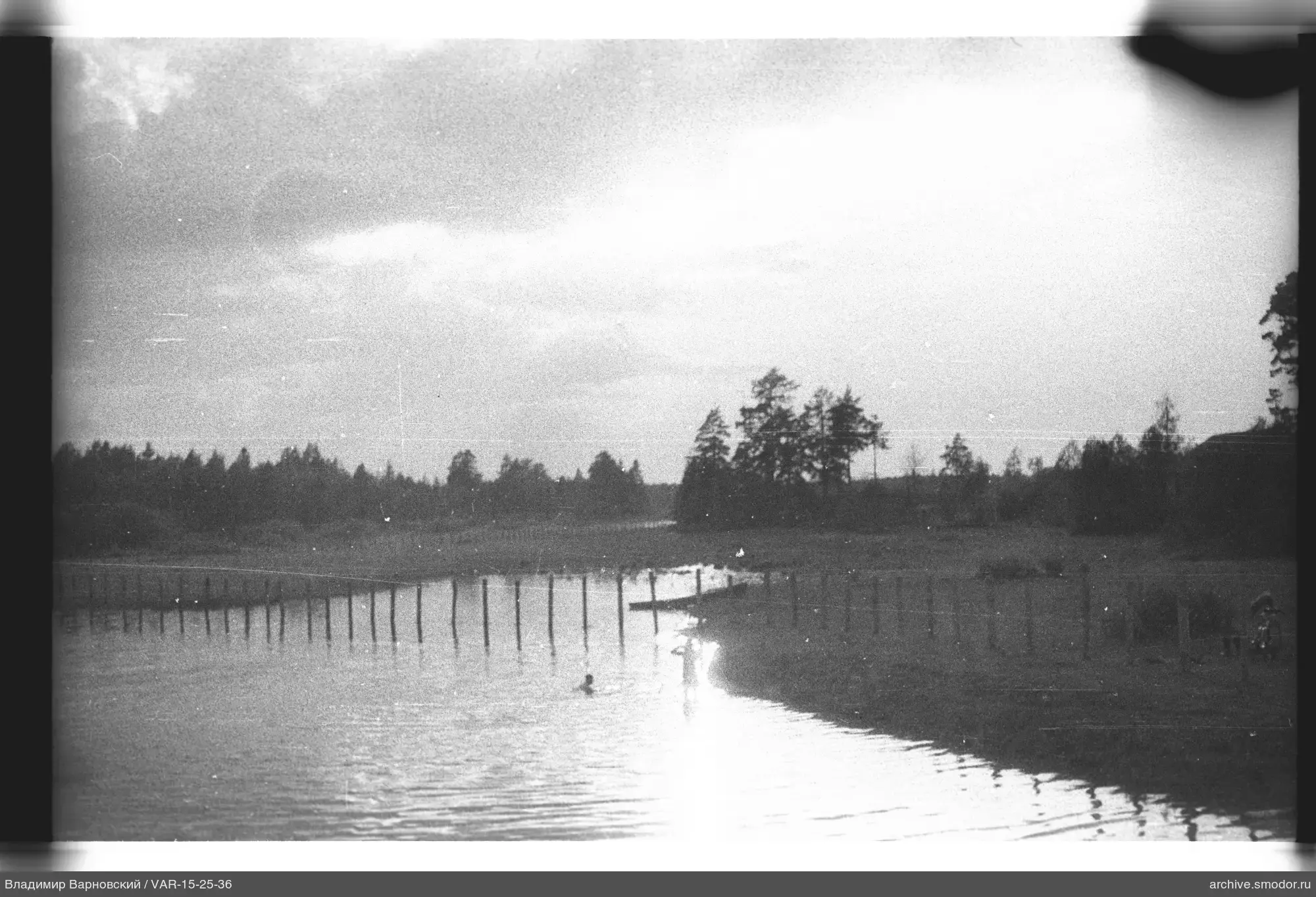 Fluss mit Holzbrücke und Personen im Wasser