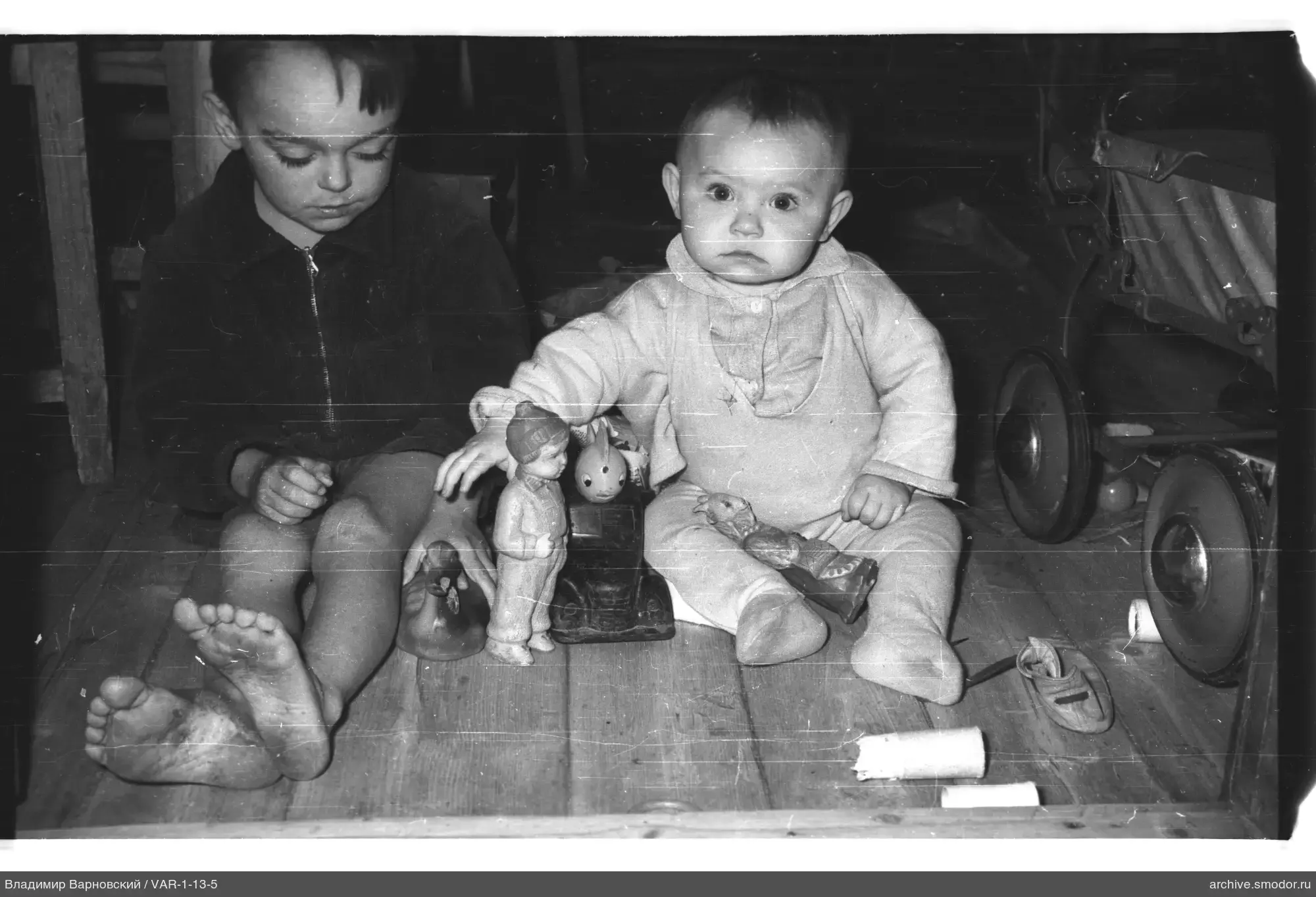 Zwei Kinder mit Spielzeug auf dem Boden