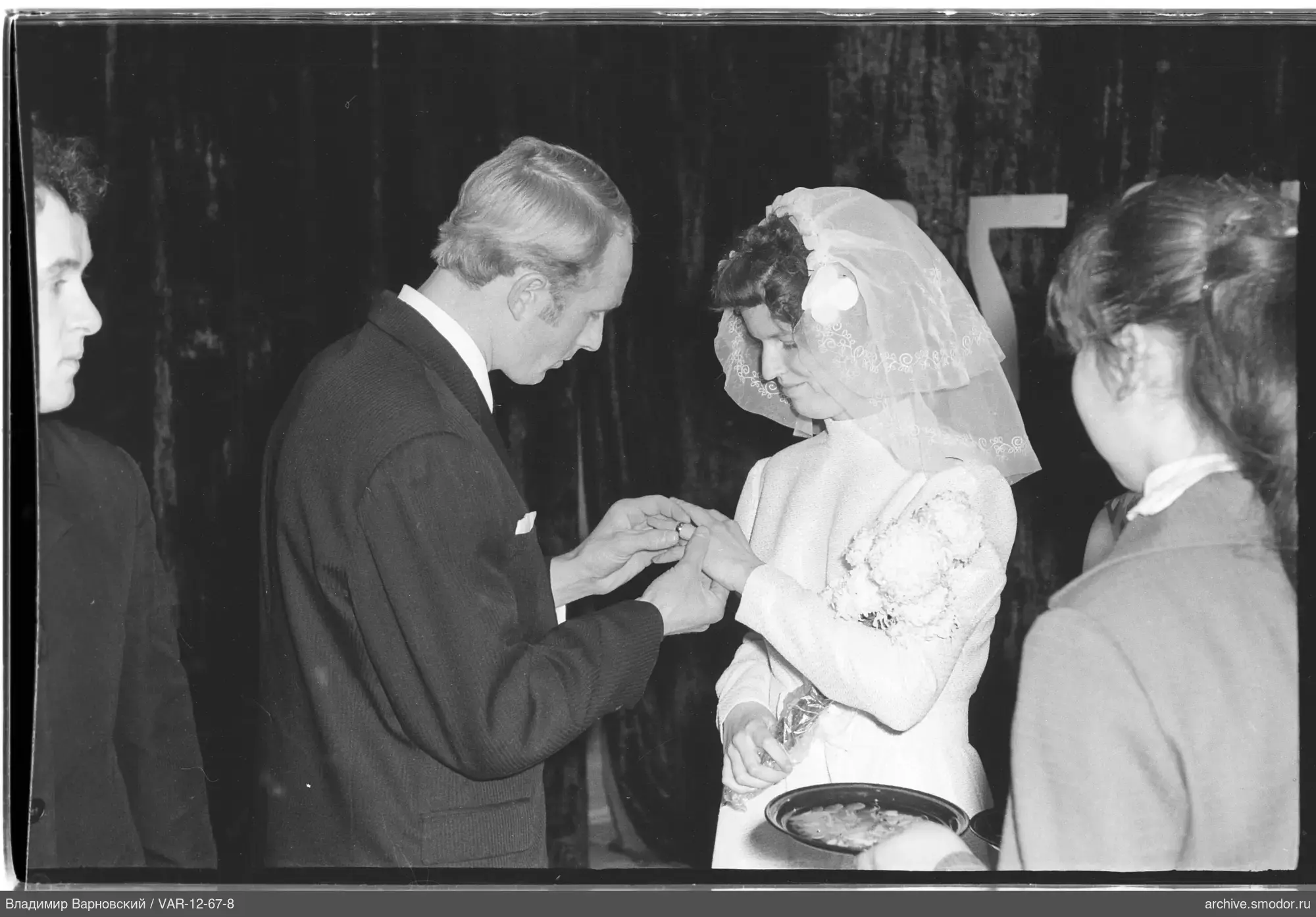 Man placing a ring on a woman in wedding dress