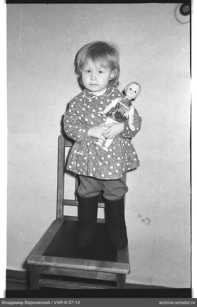 Mädchen mit Puppe auf Stuhl