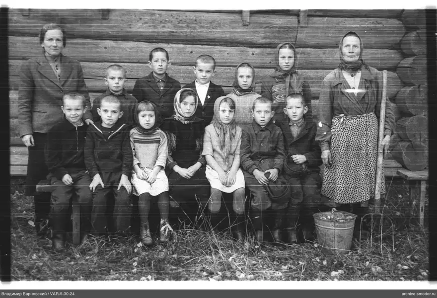 Gruppe von Kindern und Frauen vor Holzwand