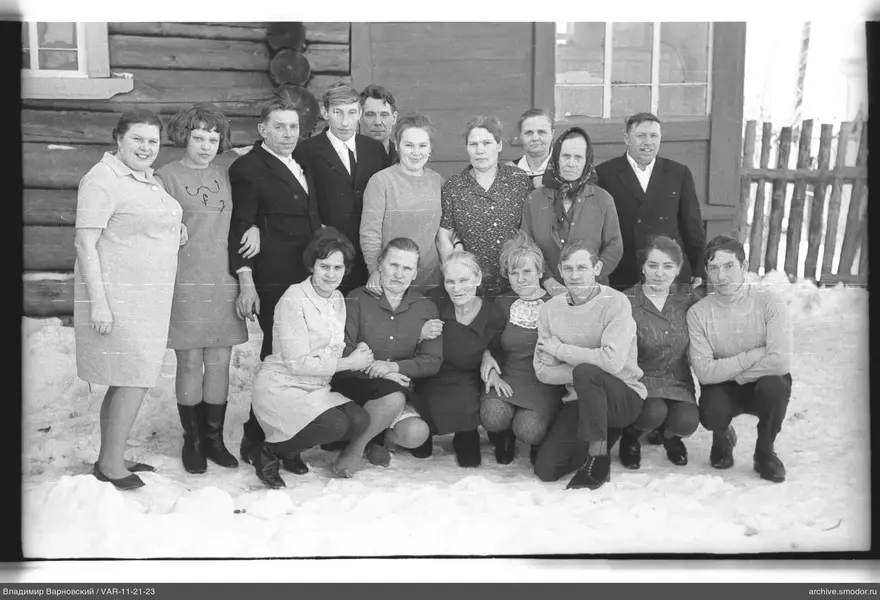Gruppe von Menschen bei einem Holzhaus im Schnee