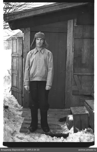 Mann vor Holzgebäude auf Schneeboden