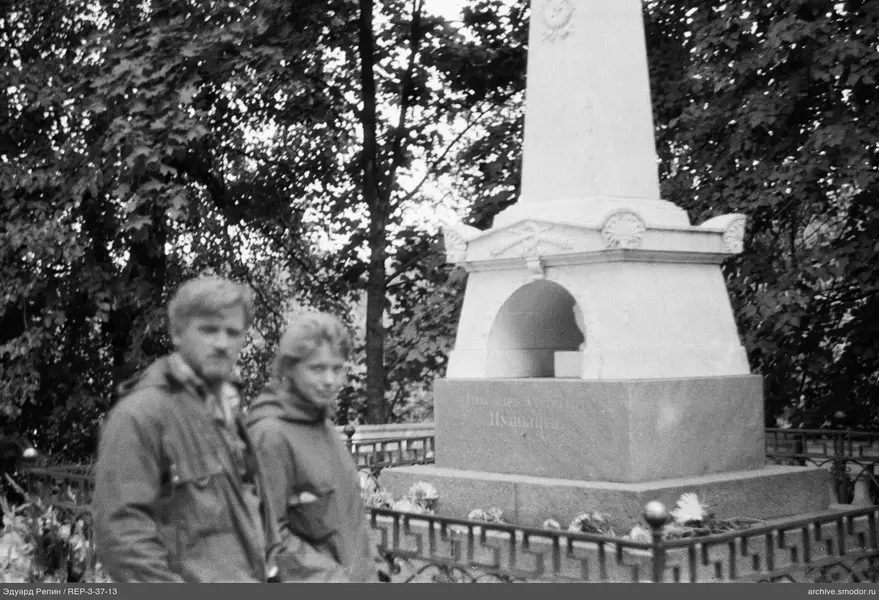 Zwei Personen bei einem Denkmal mit Reliefs