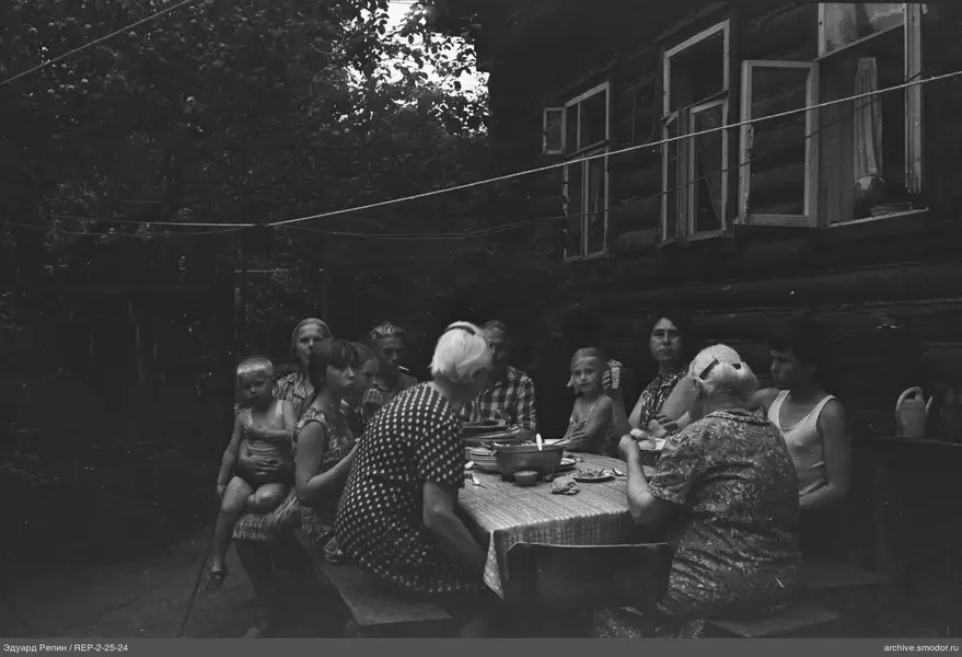 Группа за столом у деревянного дома