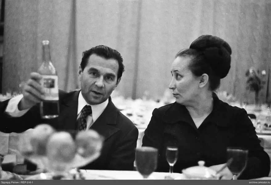Mann mit Flasche und Frau am Tisch