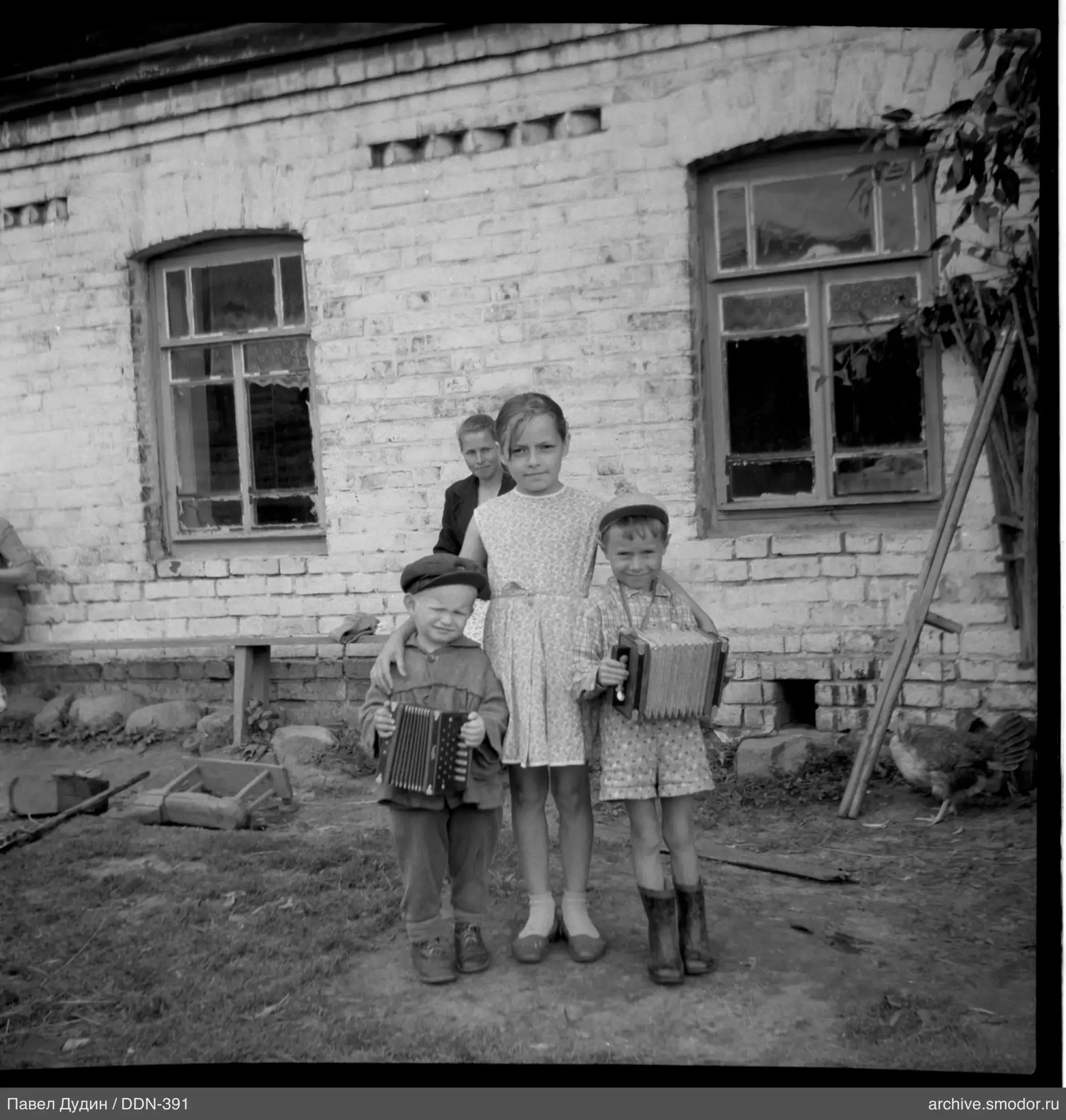 Gruppe von Kindern und Frau bei Backsteinhaus