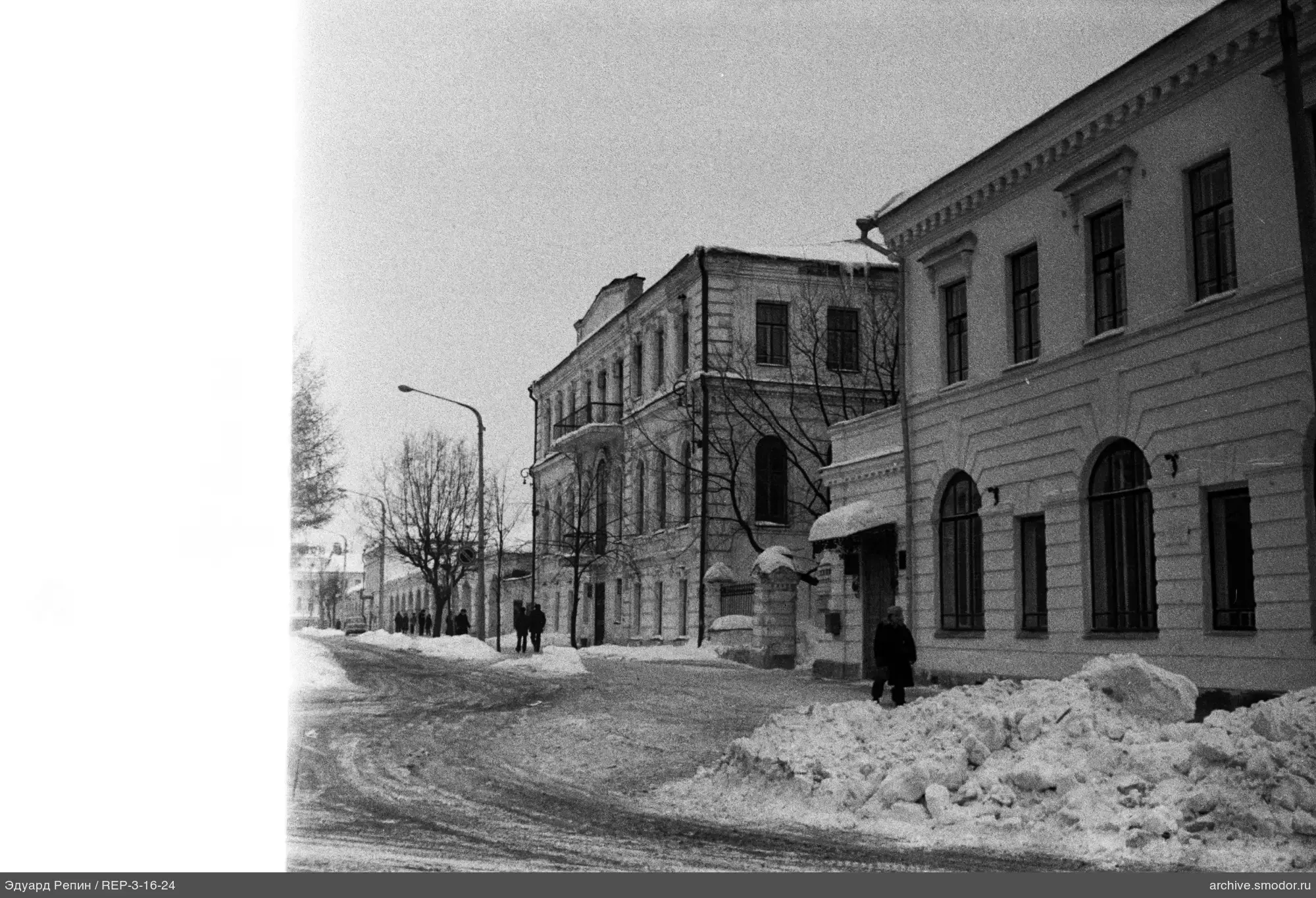 Улица с заснеженным тротуаром и зданиями