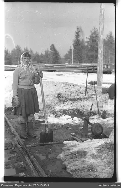 Woman with shovel by railway tracks