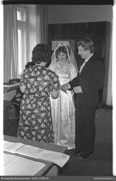 Three people with documents and books in a room