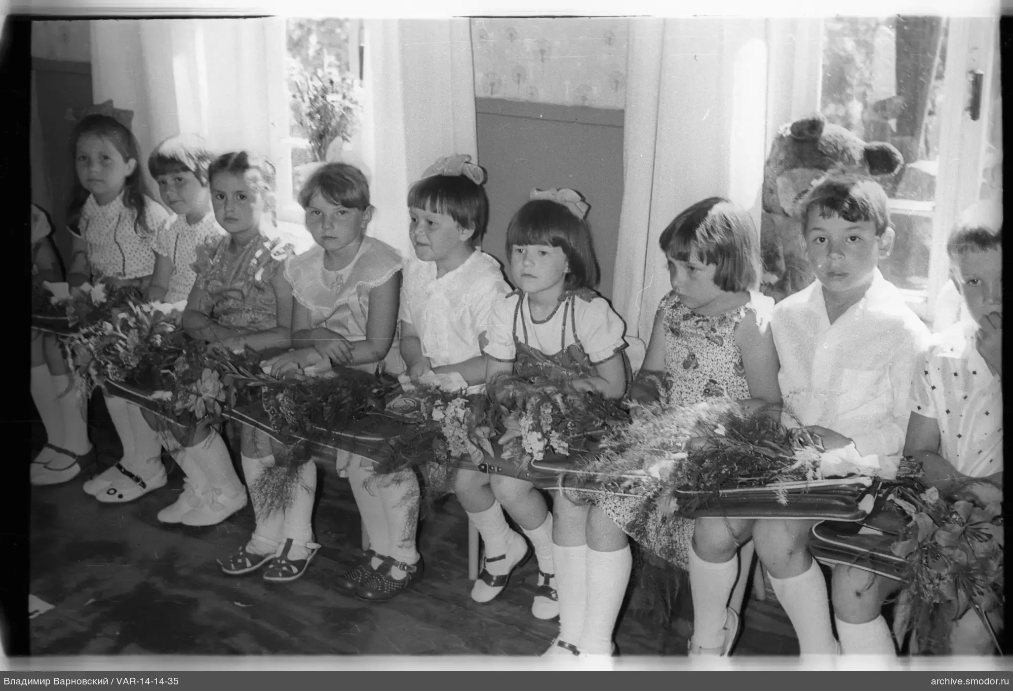 Kinder mit Blumensträußen und Plüschbär